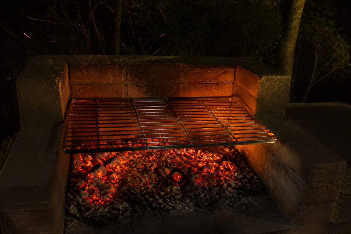 A built brick braai at night, coals glowing under the grid